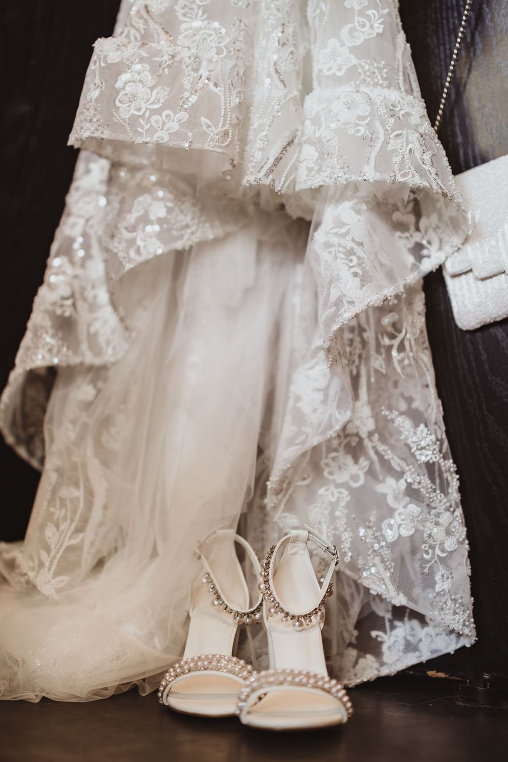 Close-up details of a white lace wedding dress and pearl-adorned bridal shoes.