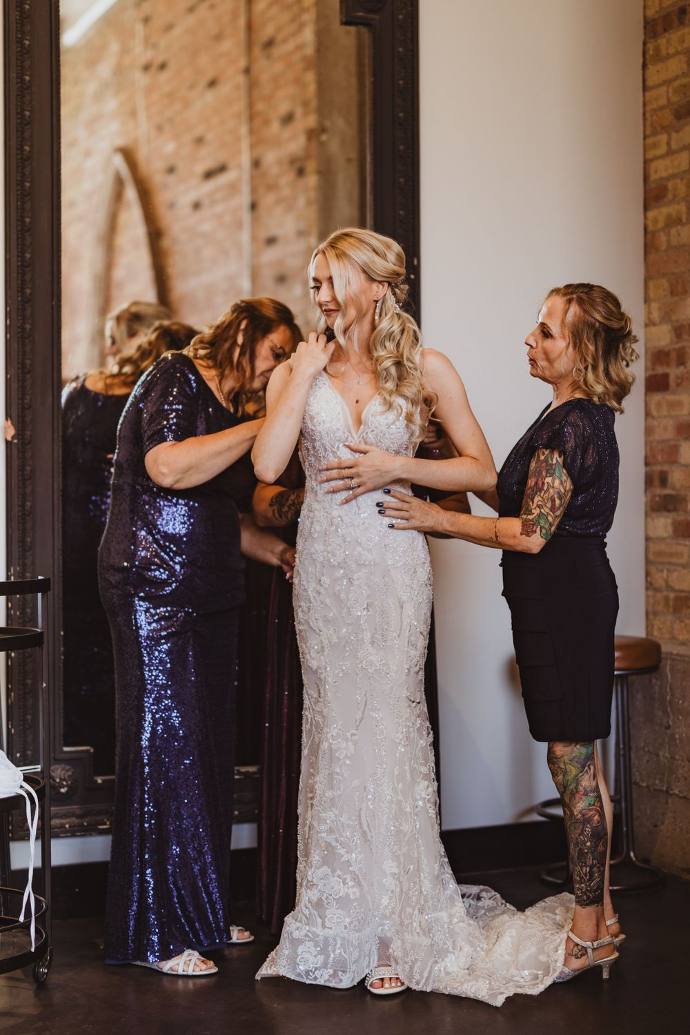 Wedding party members in navy sequin dresses embrace in an emotional moment.