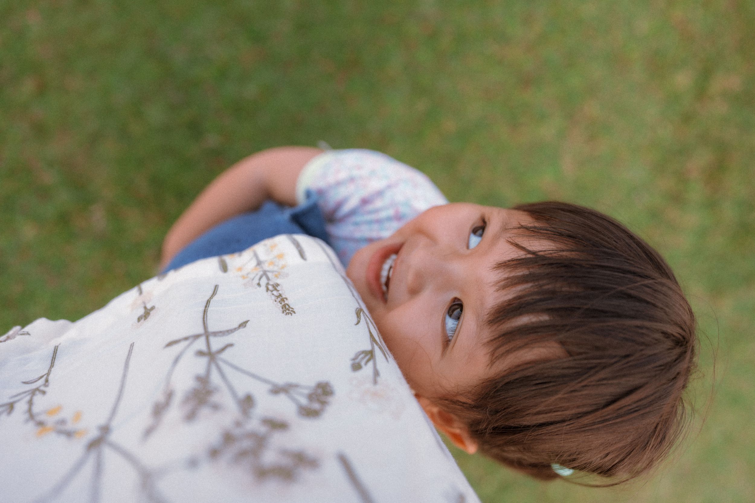 A young child looking upward with an inquisitive expression against a green background.