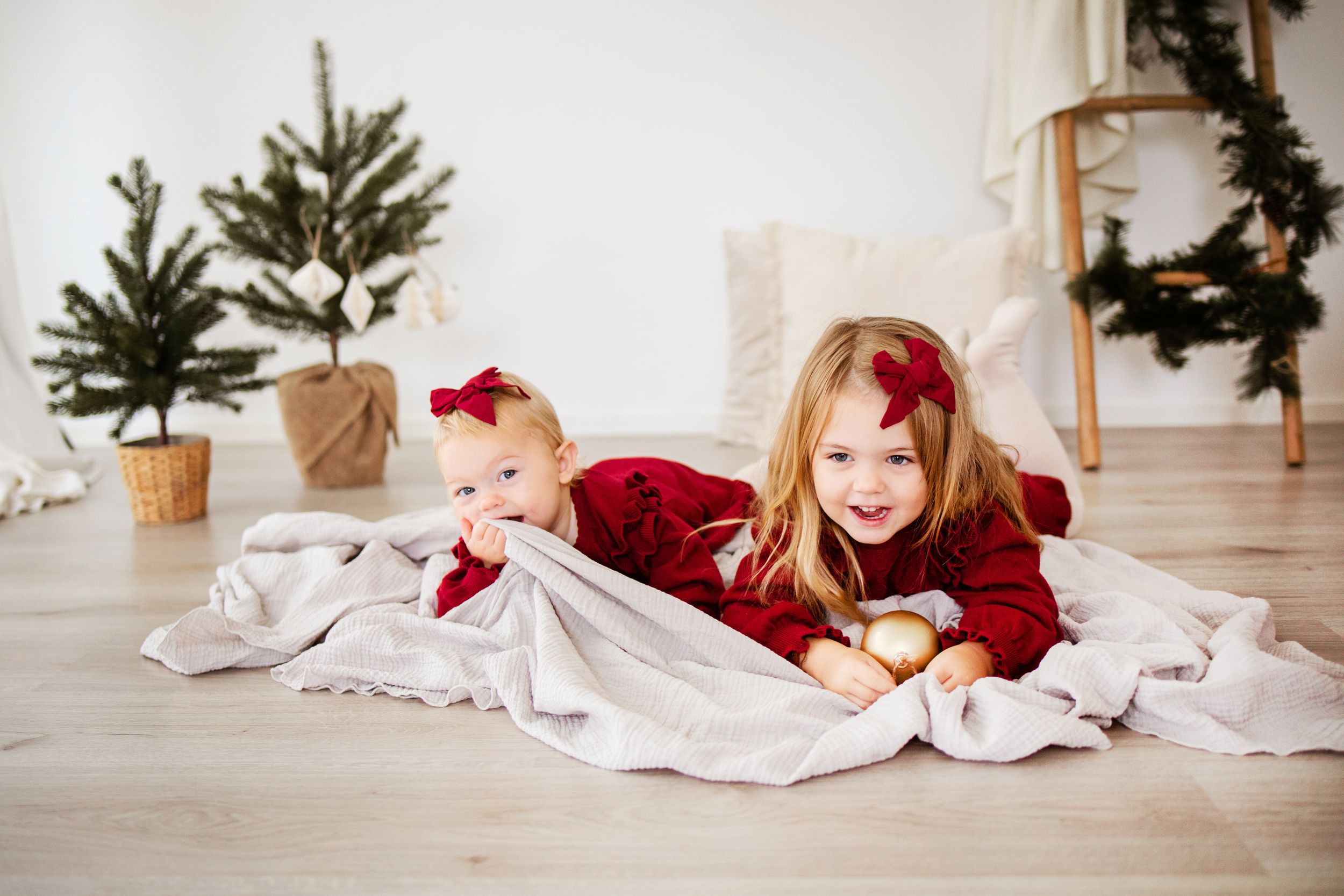 A series of festive holiday photographs show someone lying in front of a Christmas tree in a cozy living room.