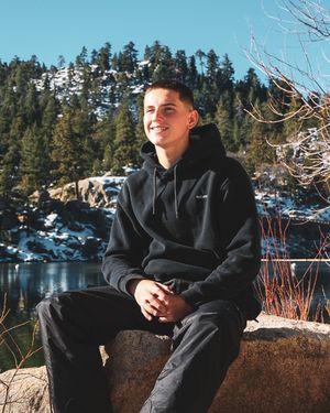 Winter scene with someone sitting on rocks overlooking a snowy landscape.