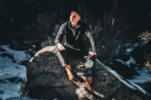 Dark atmospheric shots of someone jumping between rocks in a snowy setting.
