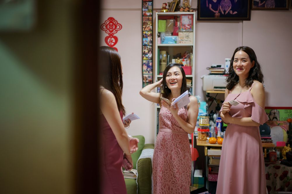 Women in pink dresses sharing joyful moment at indoor celebration.