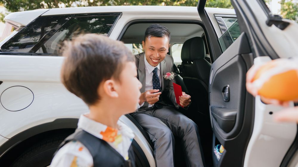 A heartwarming interaction between a groom and child through a car door on wedding day.