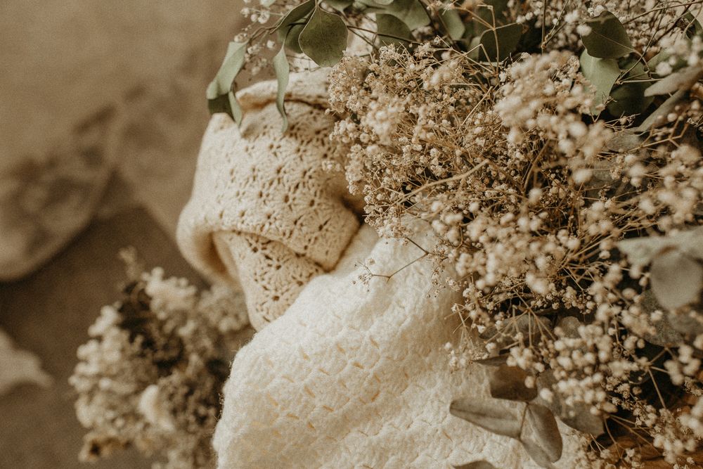 Delicate lace fabric draped with sprays of small white baby's breath flowers in a soft sepia-toned image. Maternity studio in Beckenham