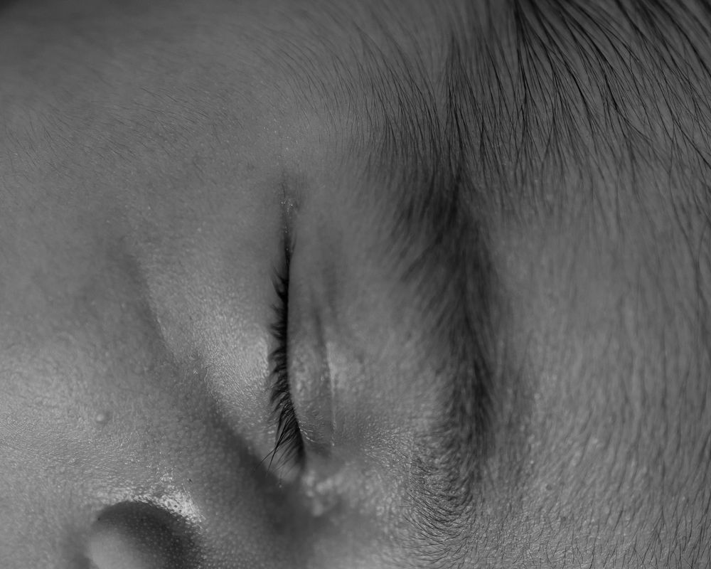 Close-up black and white detail of a sleeping baby's eye and nose.