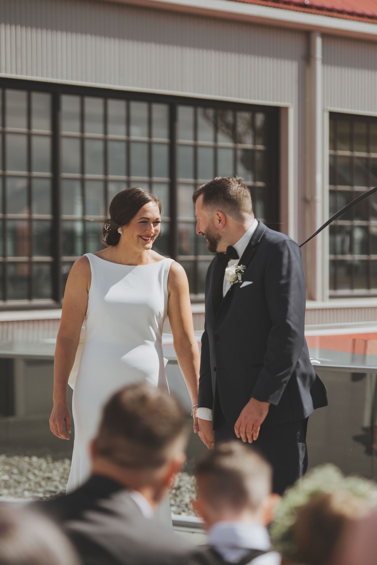 A joyful wedding ceremony moment between couple in sleek white dress and classic black tuxedo.