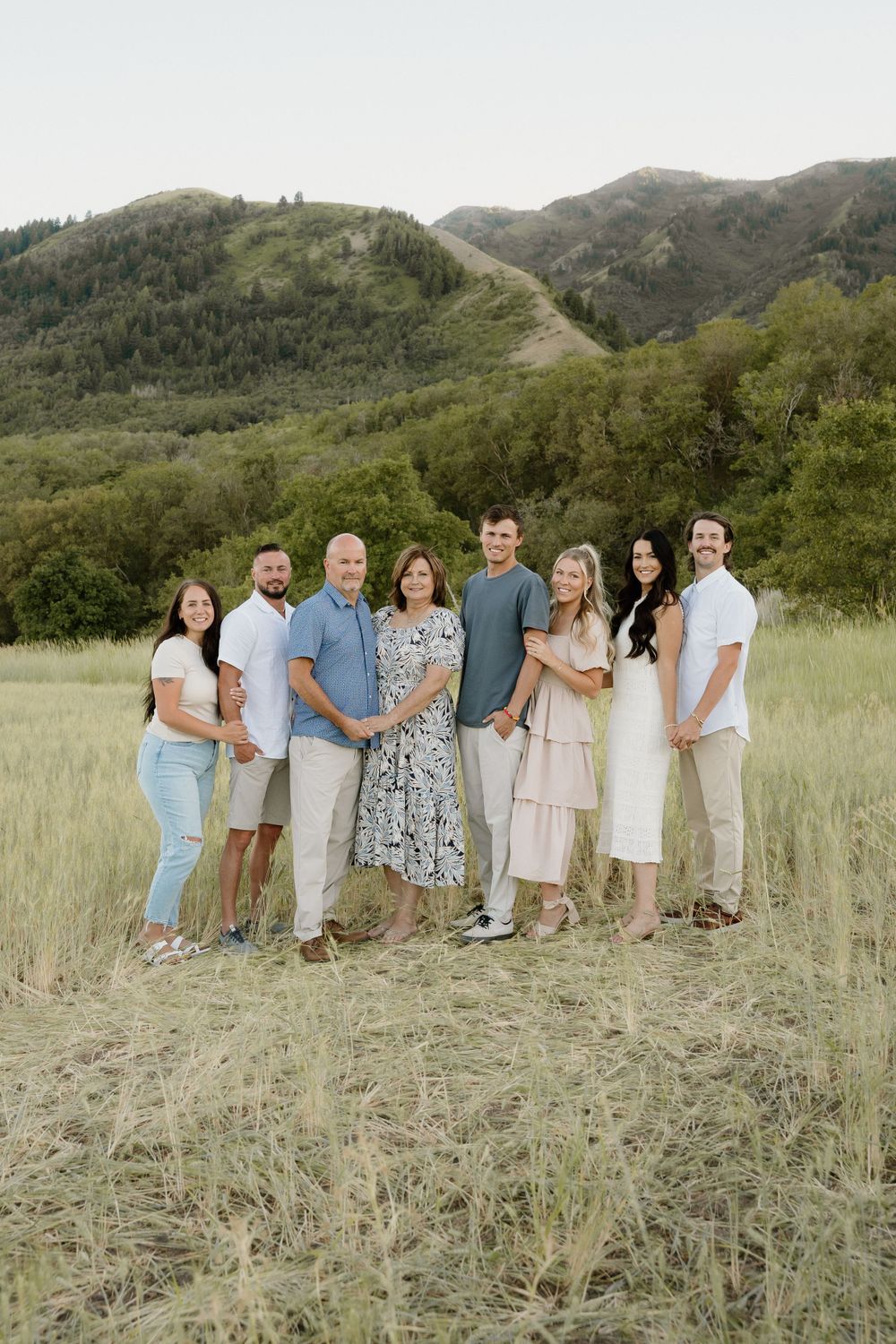Group portrait of family members in coordinated outfits against mountain landscape.