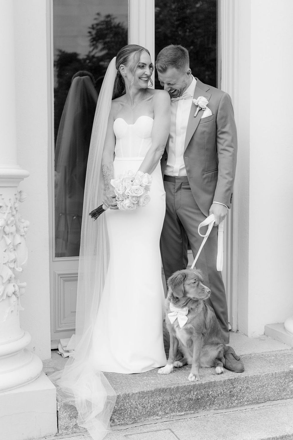 A wedding couple stands on white steps with their small dog sitting beside them in a series of black and white photos.