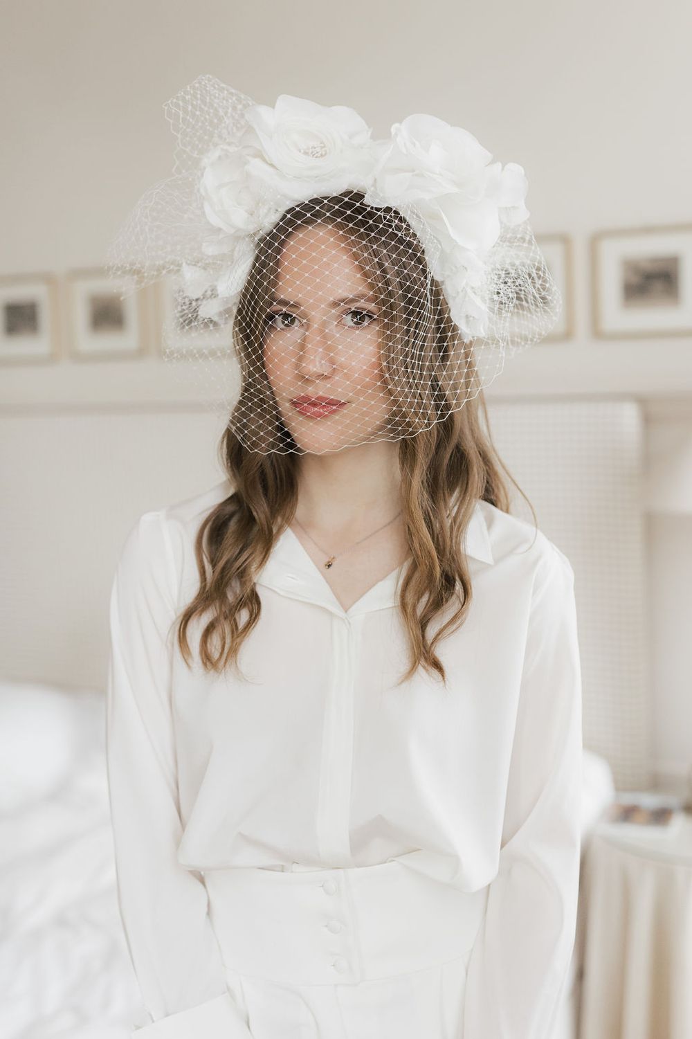 Bride in white dress and vintage-style veil poses in bright indoor setting.