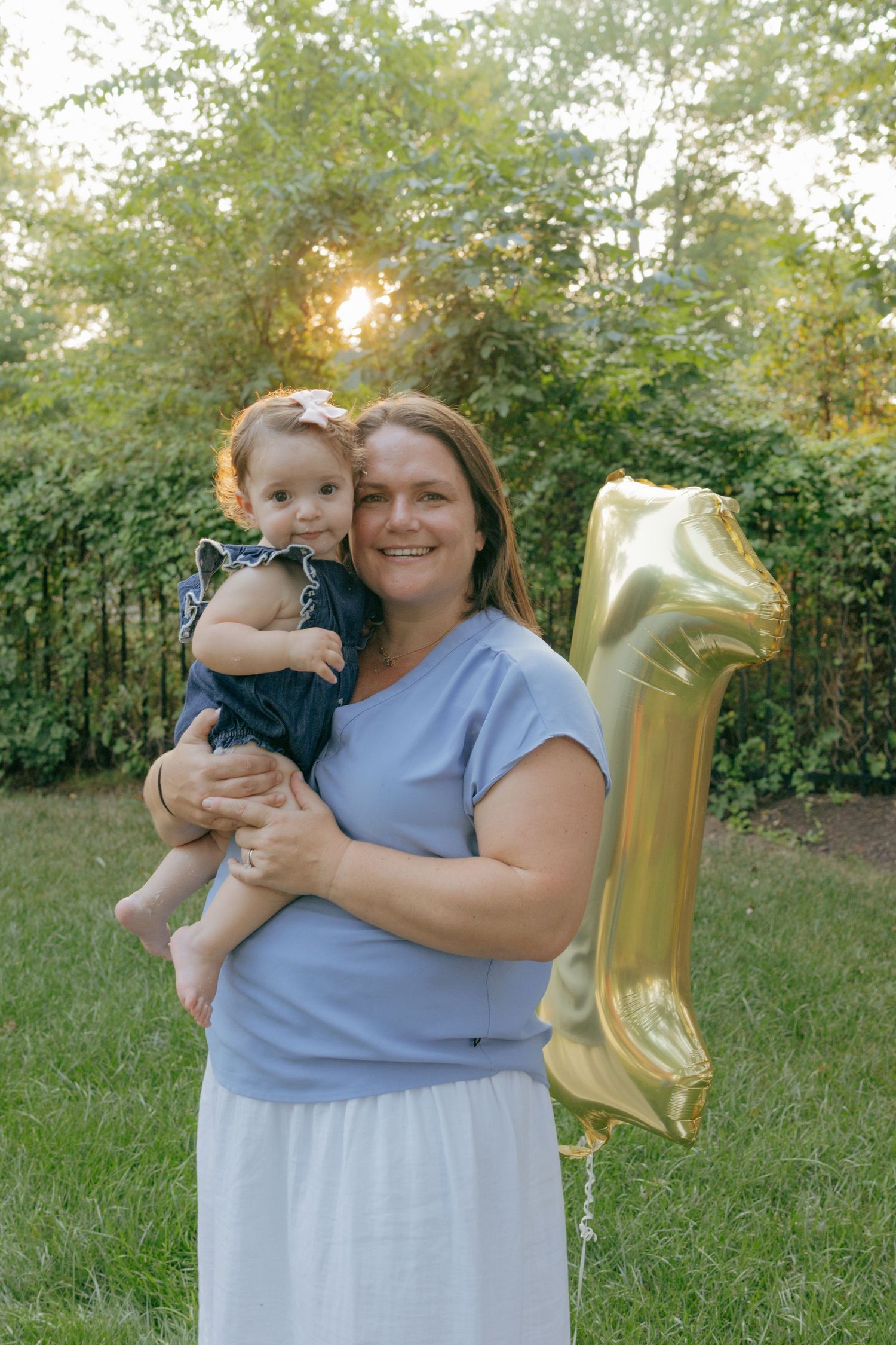 Outdoor family celebration with gold number one balloon in a garden setting.
