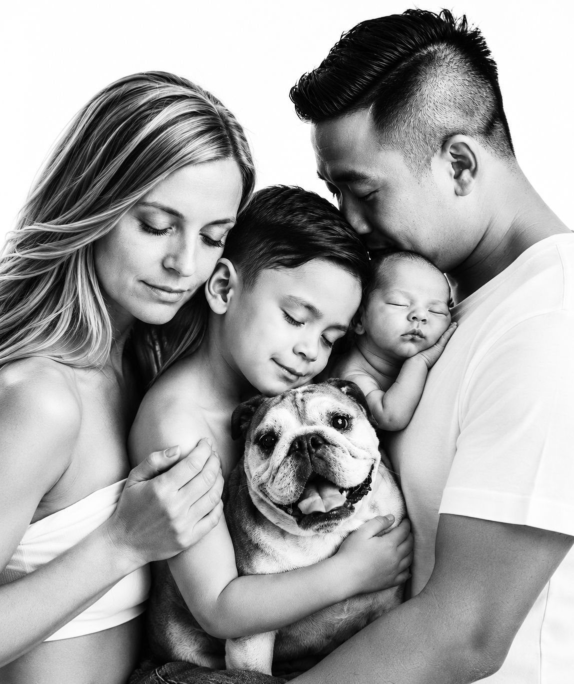 Black and white portrait of a family cradling a newborn baby with tender expressions.