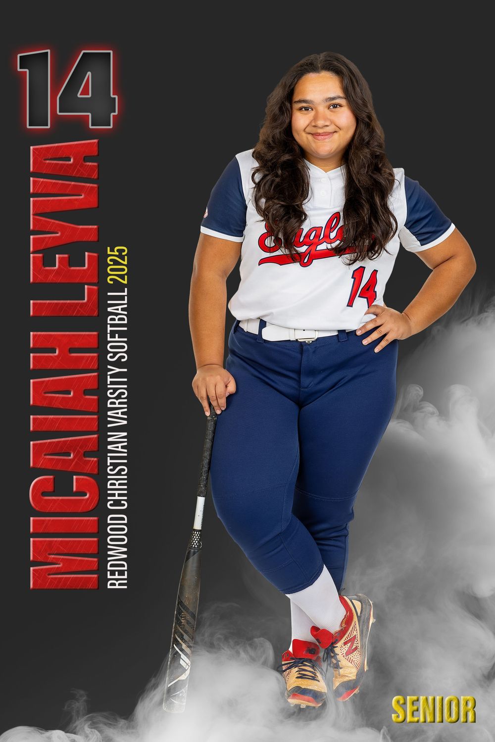 Softball player in white and navy uniform posing with bat against smoky background.