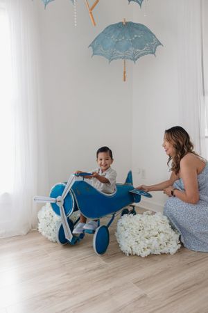 Indoor photo setup with blue toy airplane and hanging parasol decorations.