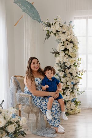 Elegant indoor portrait setting with hanging parasol and cascading white floral arrangements.