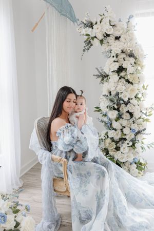 Dreamy portrait session featuring soft blue tones, white flowers, and delicate parasol decor.