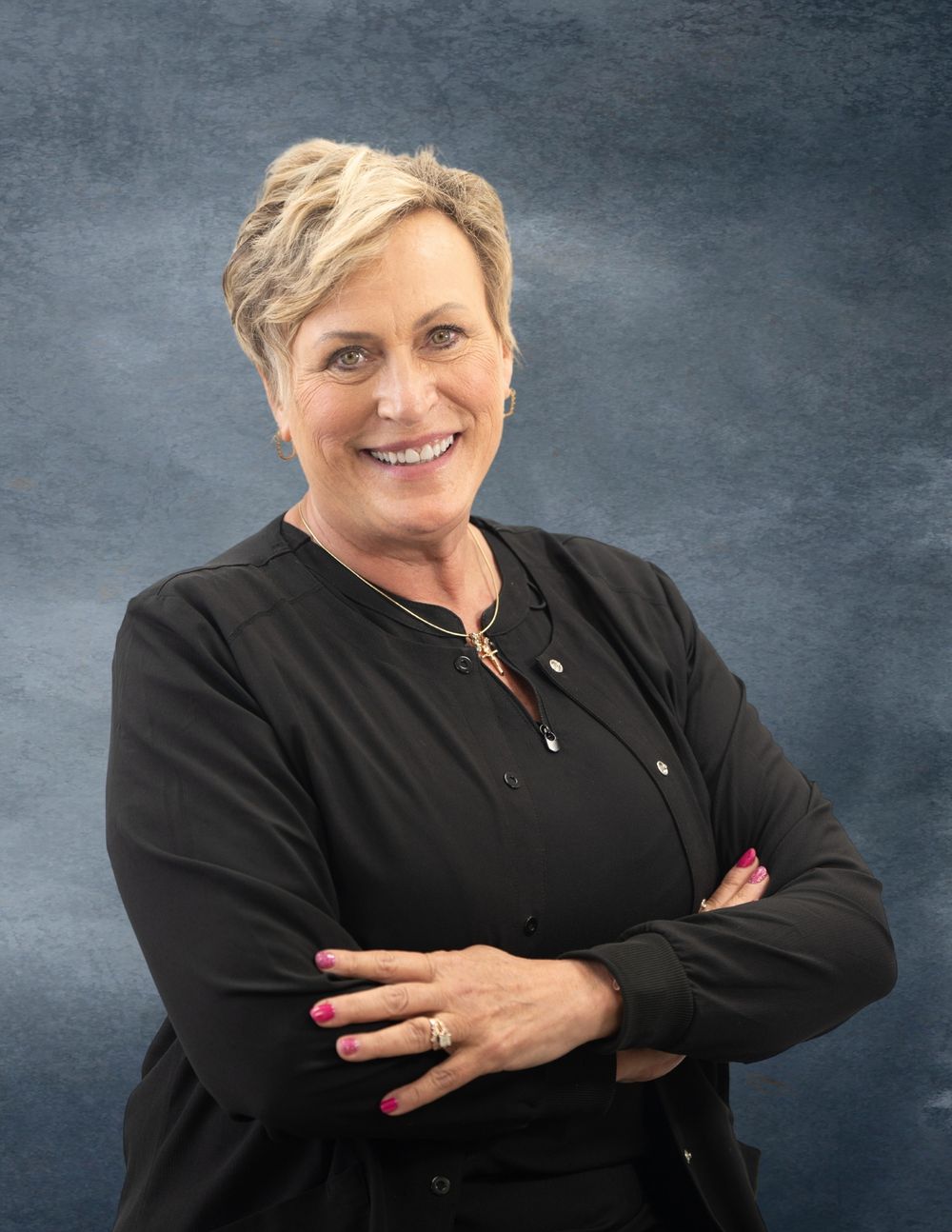 Professional in black top poses confidently against gray background. Quad Cities Business Headshot Photography