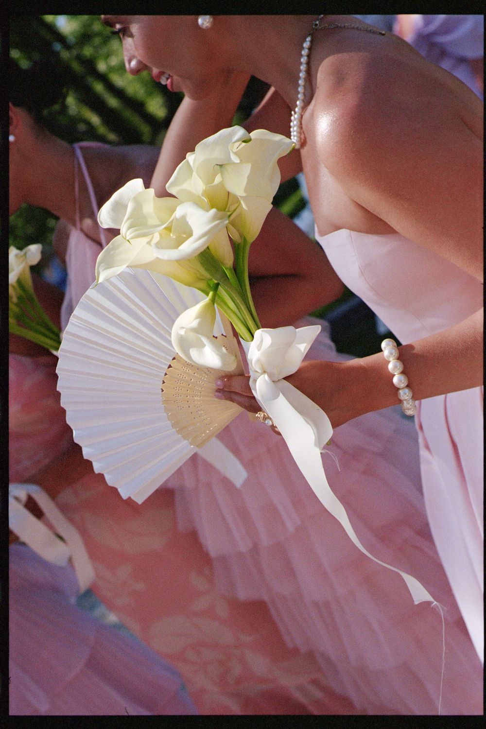 Sequence of photos showing a white calla lily flower being gently held against a soft pink background.