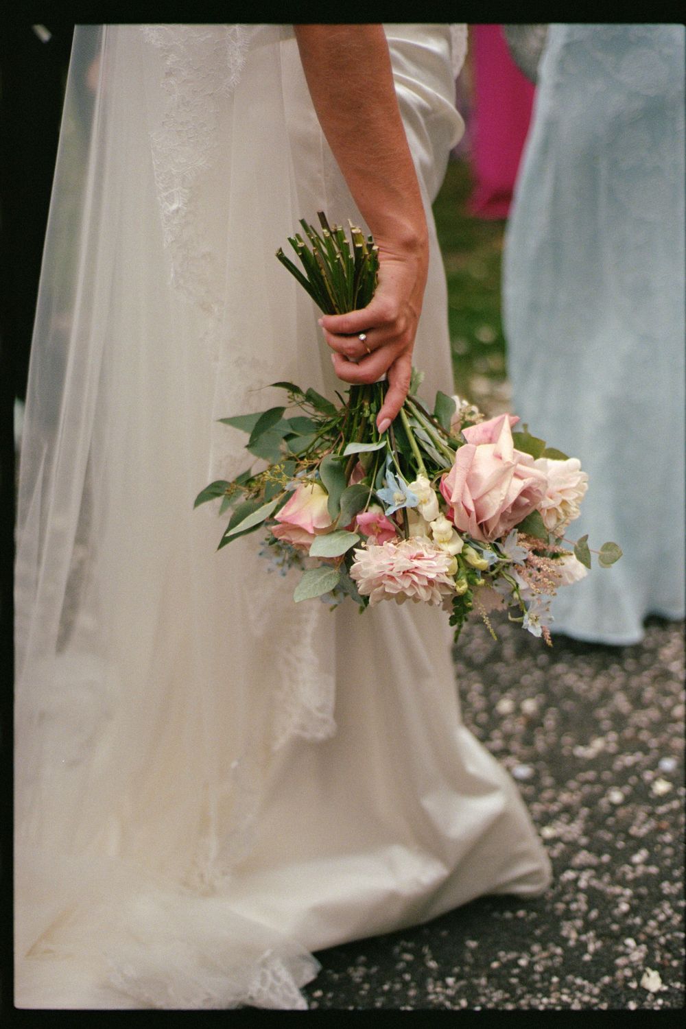 Close-up of a bride holding a delicate pink and white bouquet with eucalyptus against her white wedding dress.