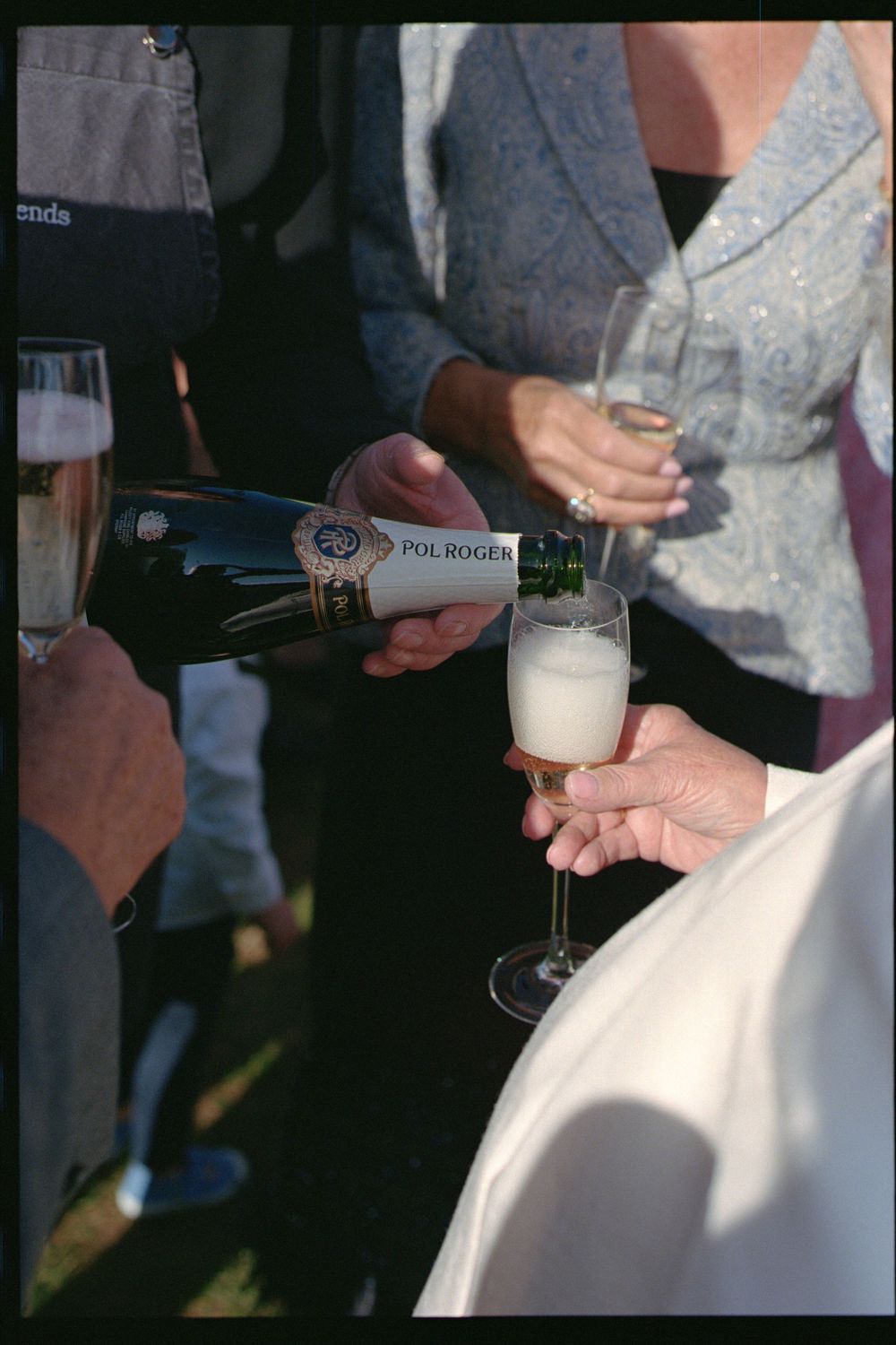 Hands pouring champagne into glasses during a celebratory event.