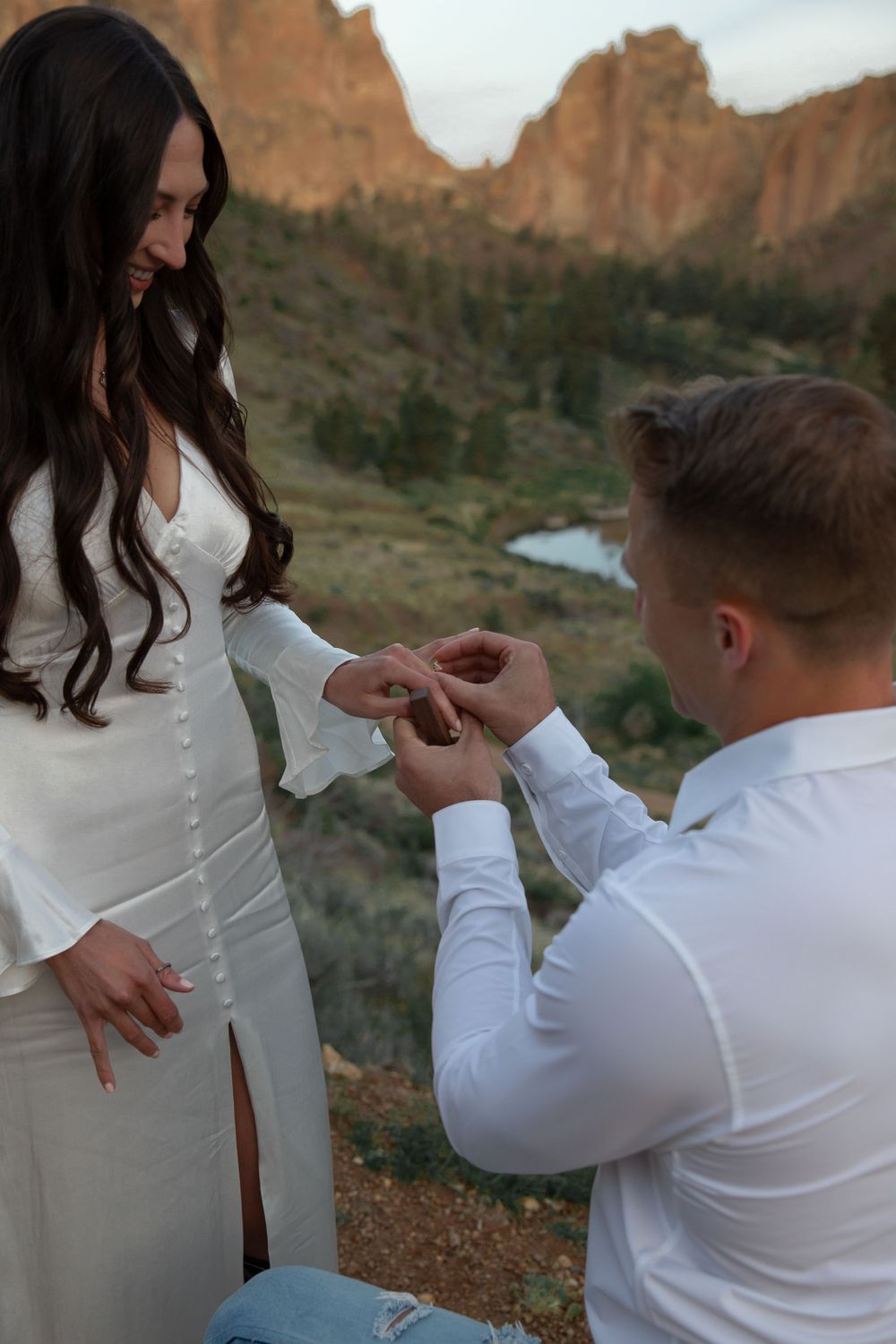 A proposal moment at Smith Rock State Park in Oregon with red cliffs and a river in the background.