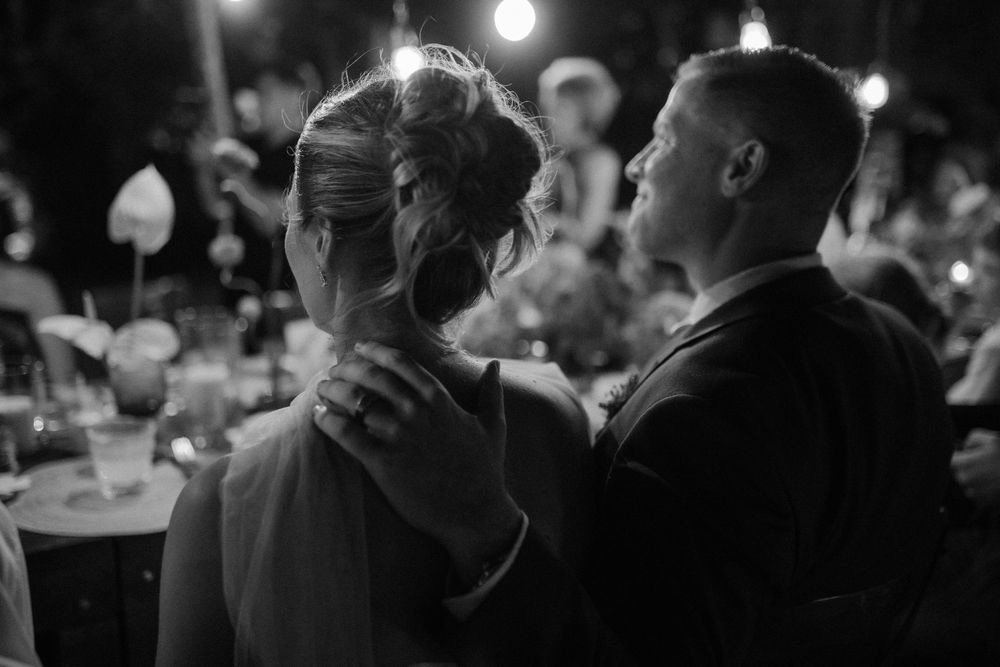 Black and white wedding photo of bride and groom sharing an intimate moment during evening reception.