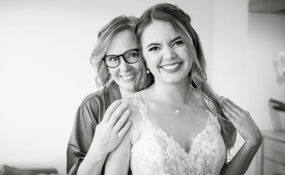 Black and white photo of a bride and older woman smiling together before wedding.