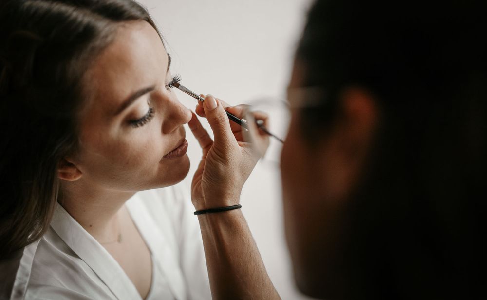 Makeup artist applying eye makeup to a bride during wedding preparations.