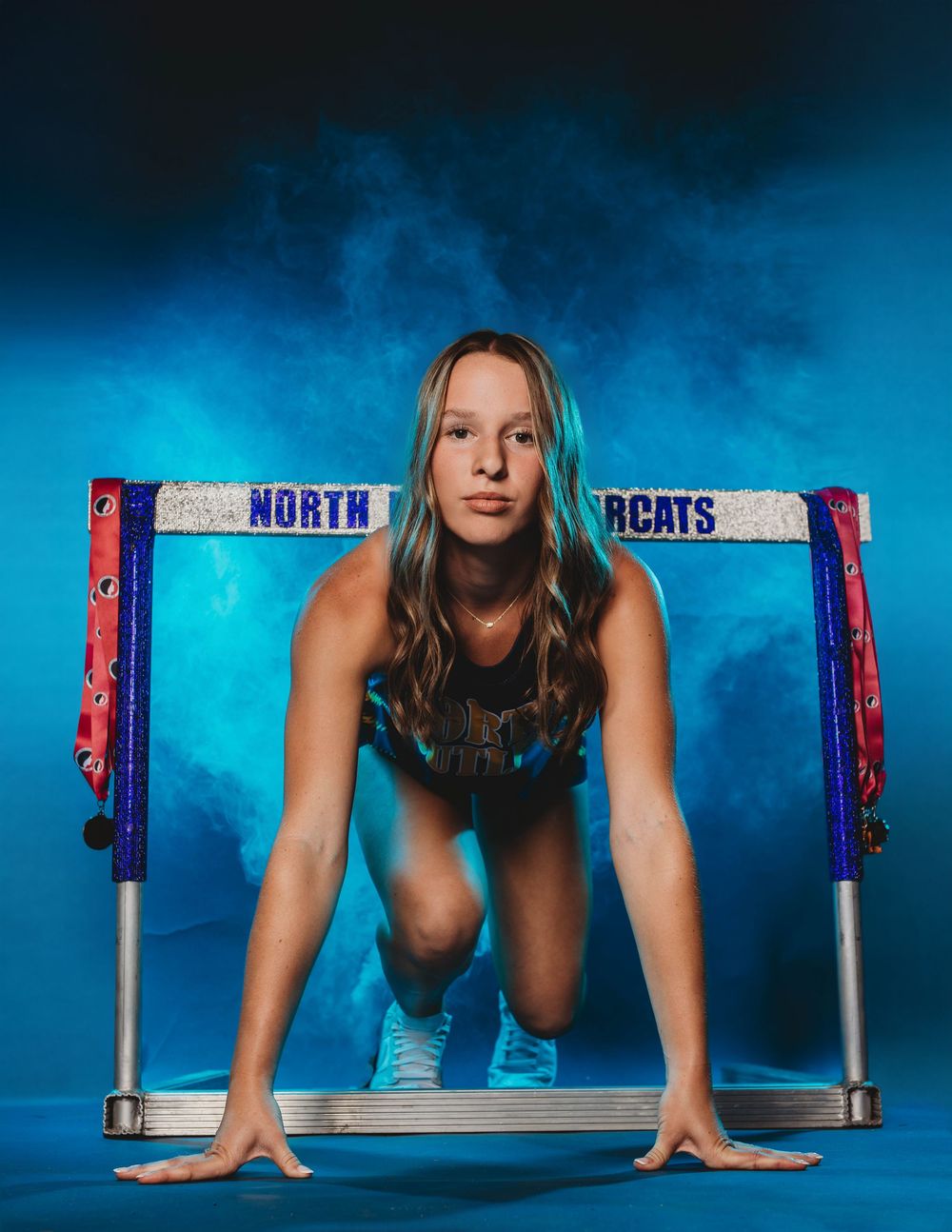 Athletic figure performs pushups against blue backdrop with North Cats banner visible.