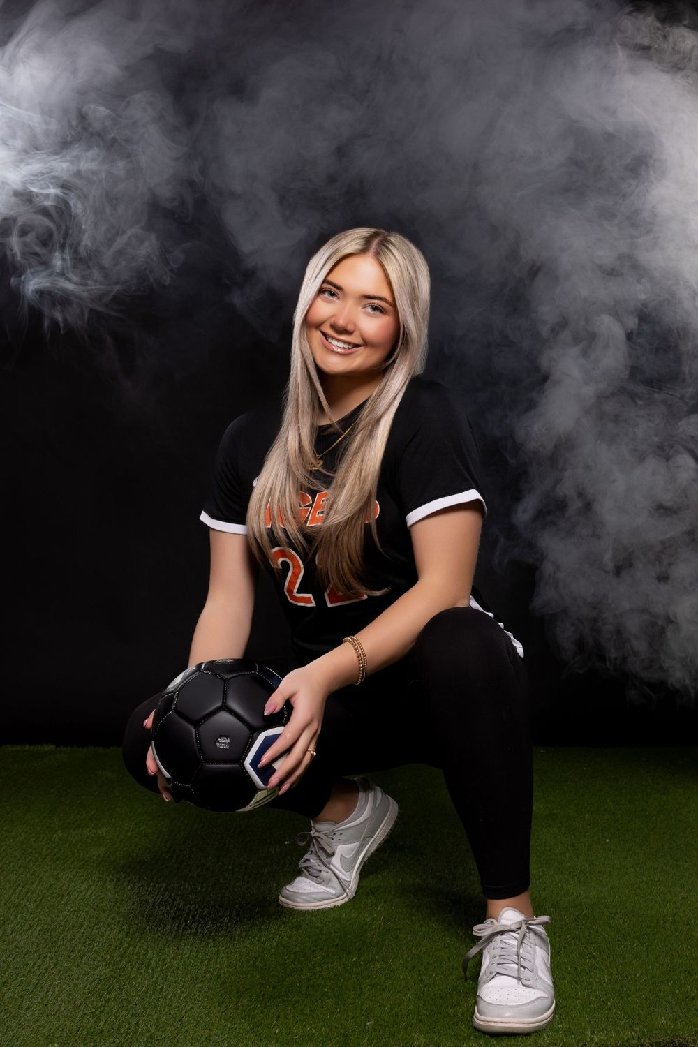 Athletic themed photo shoot with smoke effects and green turf floor.