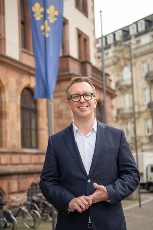 Professional portrait series showing a person in a navy suit and glasses against a historic building backdrop.