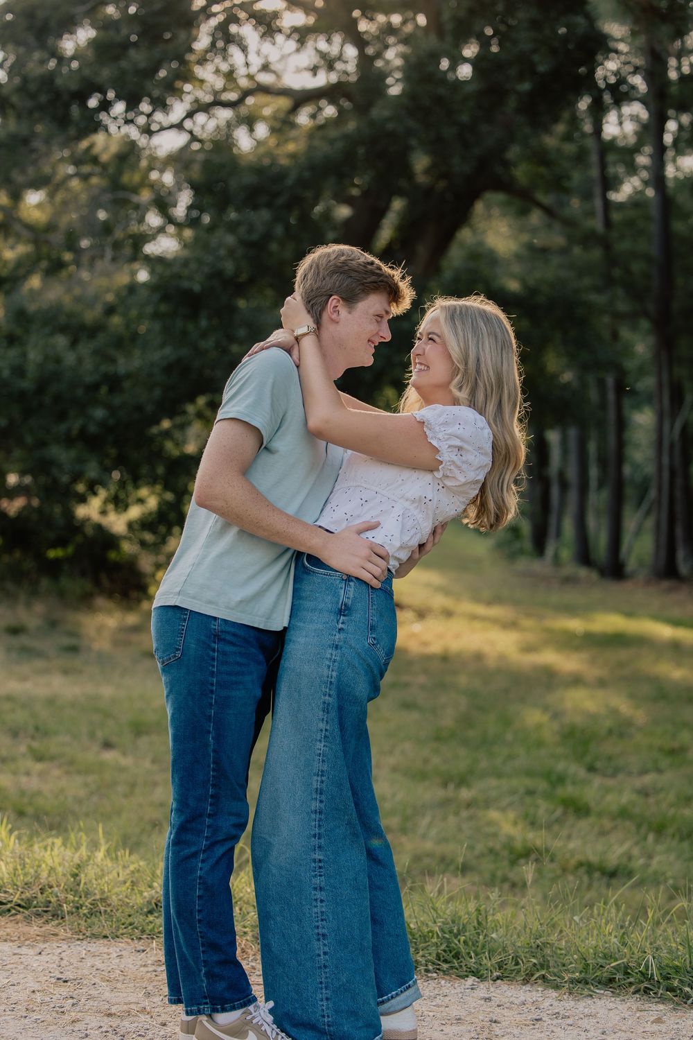 Happy couple embraces and smiles at each other during golden hour outdoor photo session.