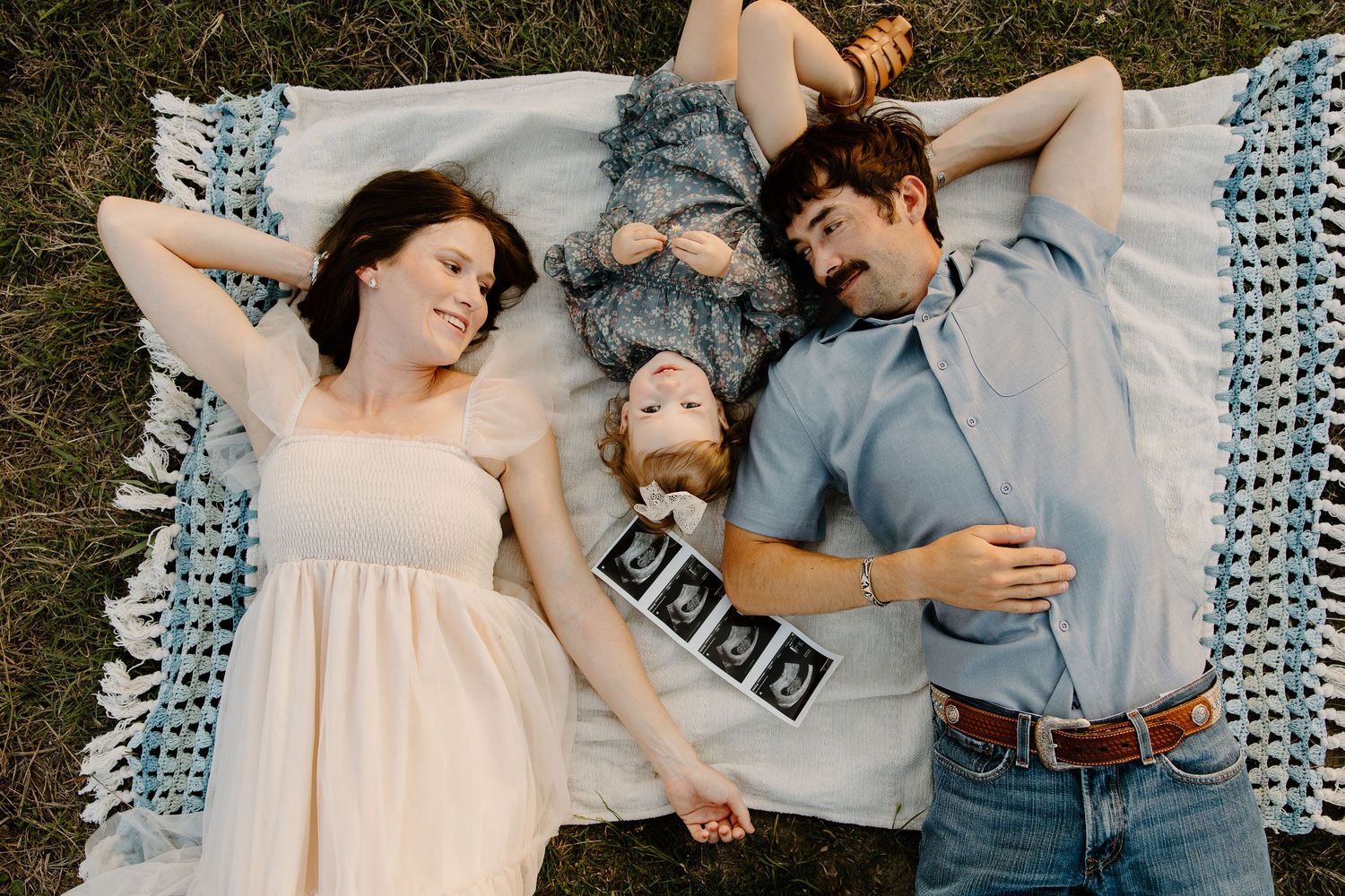 A family lying on a blanket together outdoors during a photo session.