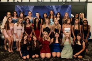 Large group photo of people in formal dresses posing together at an event.