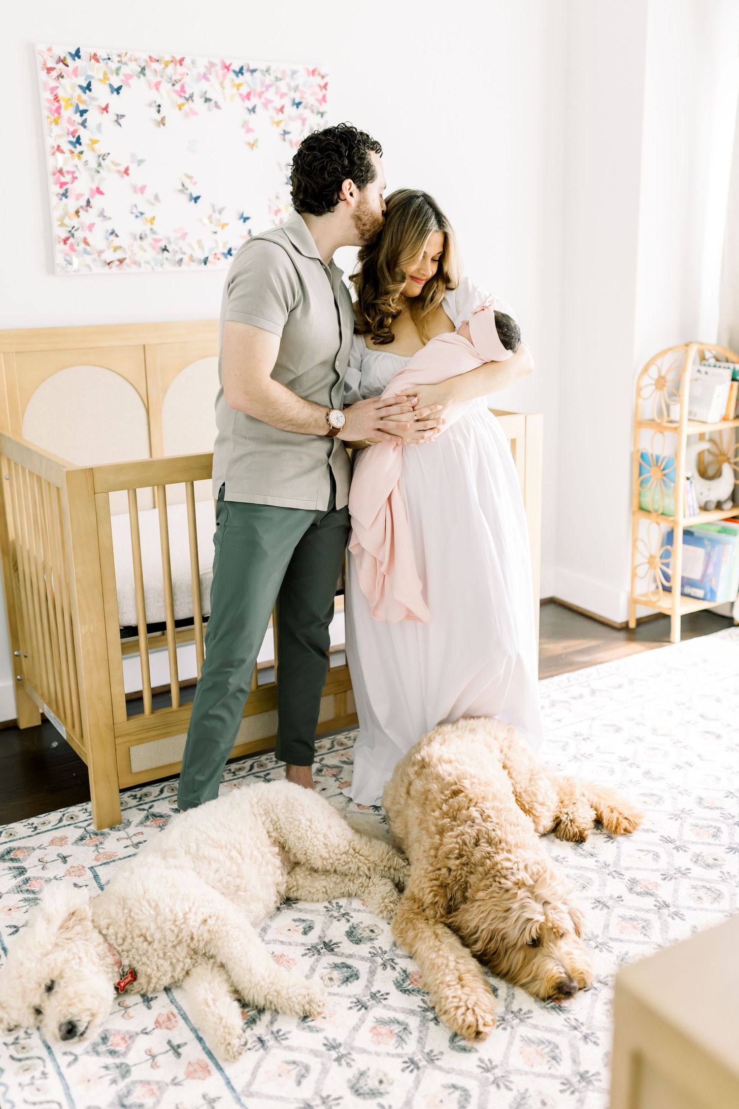 Cozy nursery scene with two dogs relaxing on patterned rug near wooden crib.
