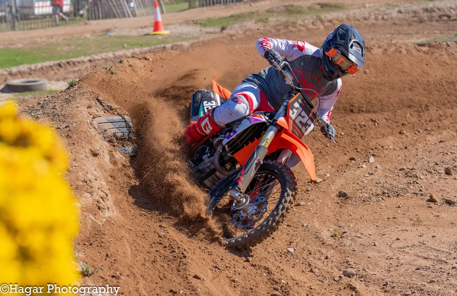An orange motocross bike number 323 drives out of a berm