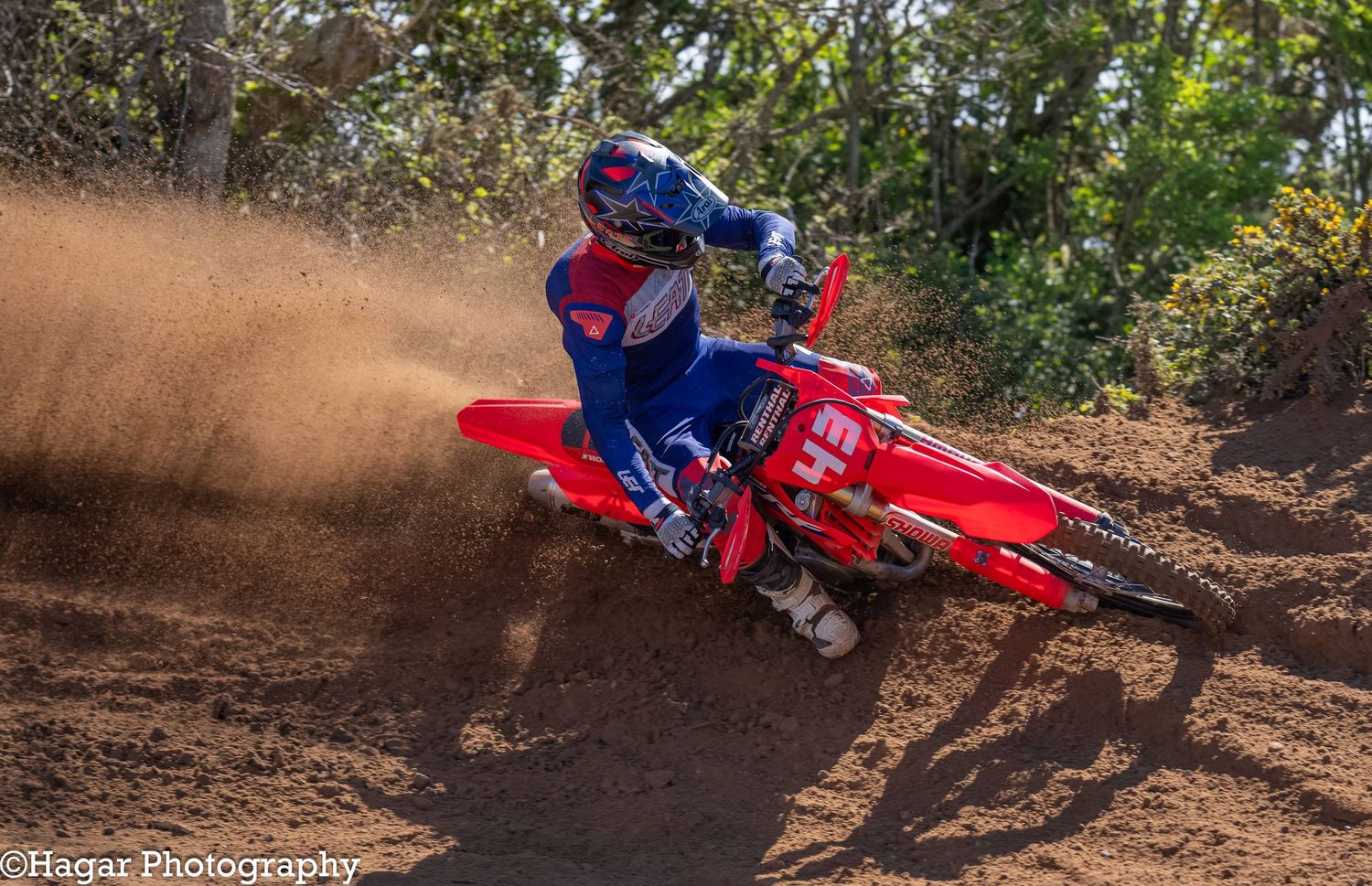 A red motocross bike number 43 drives out of a berm