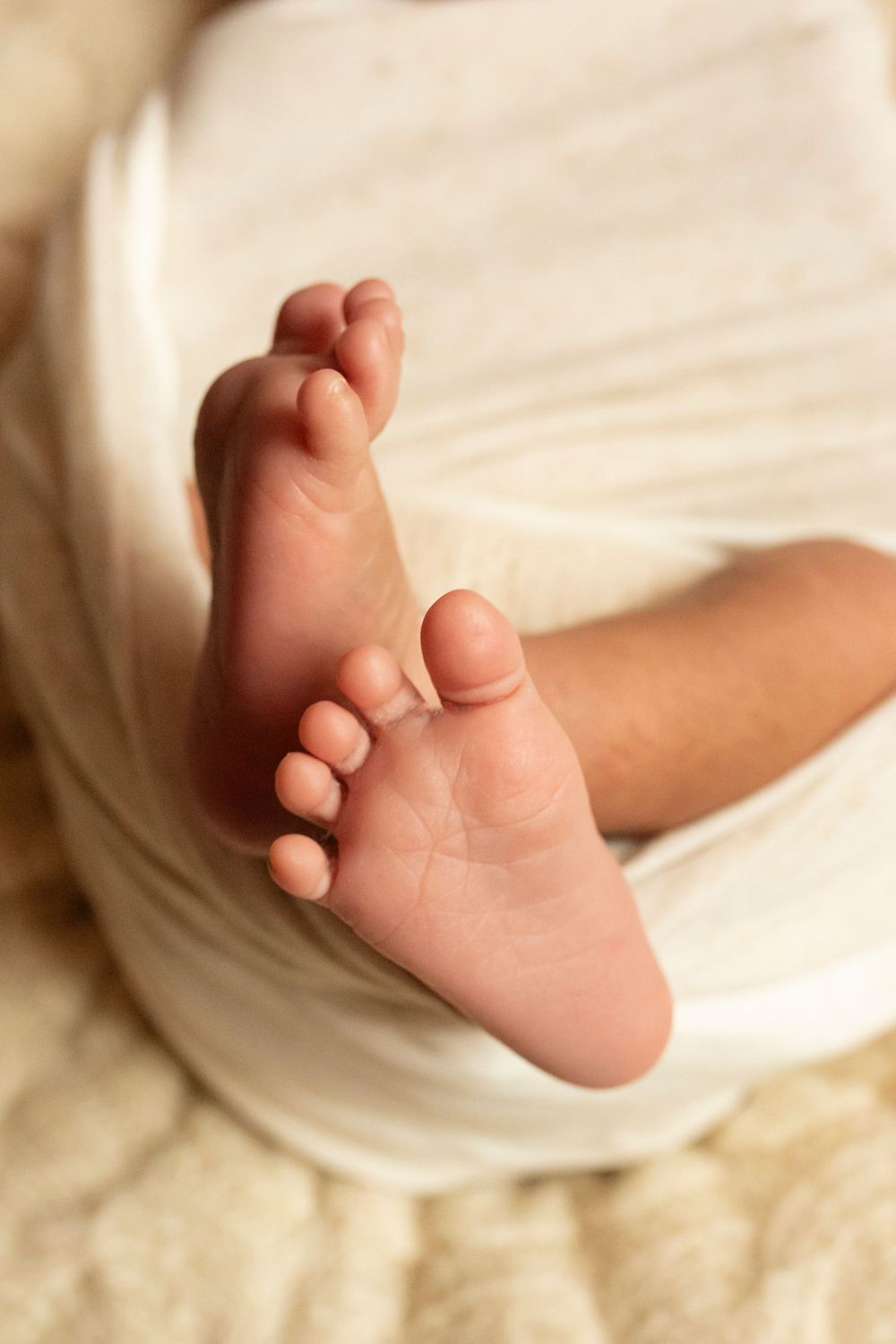 Close-up photos of tiny newborn feet against white fabric.