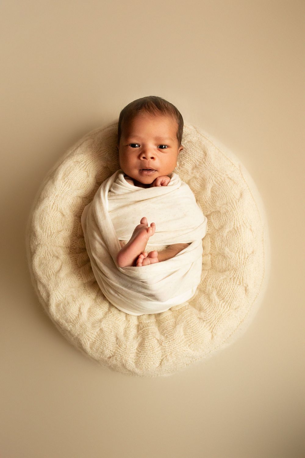Newborn baby posed on cream-colored fluffy blanket in various angles.