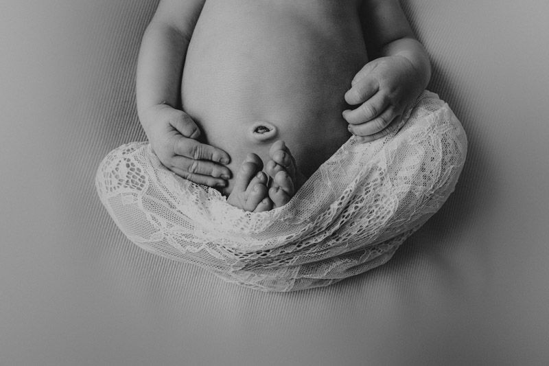 Black and white image of tiny hands resting on white lace wrap.