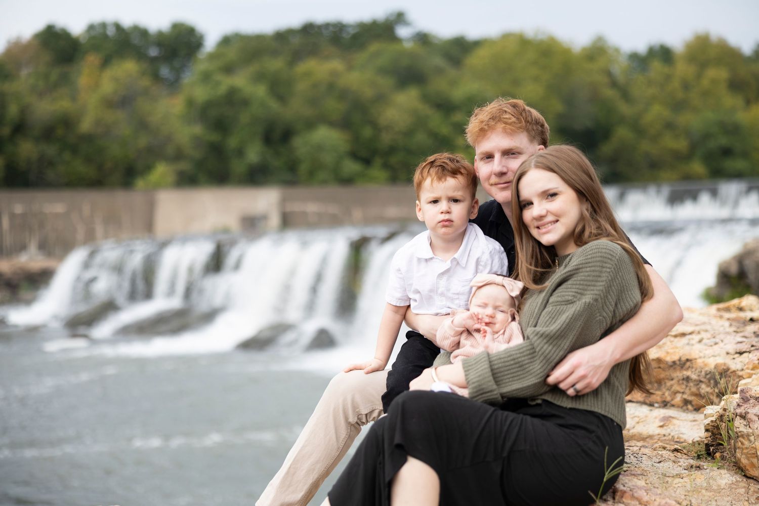 Happy family enjoying outdoor portrait session by cascading waterfall.