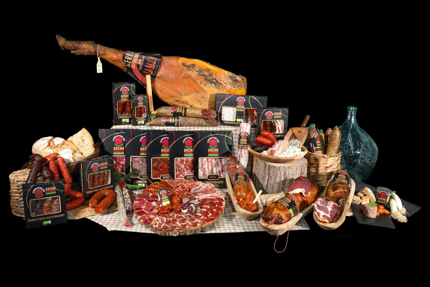 Crivencar, Tierra Astur, embutidos y charcutería con jamón ibérico, quesos y vino sobre fondo negro.
