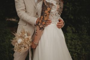 Detail shot of wedding couple with dried flower bouquet and lace dress details.