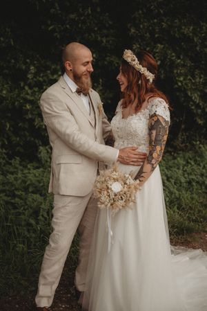 A rustic wedding portrait featuring the couple in light beige and white attire.