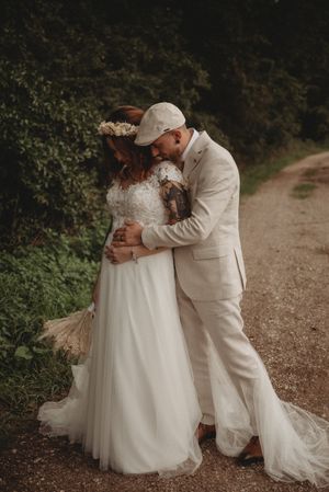 A tender moment between newlyweds on a tree-lined path in natural lighting.