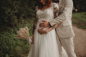 An intimate wedding photo showing the couple with dried flower bouquet on a garden path.