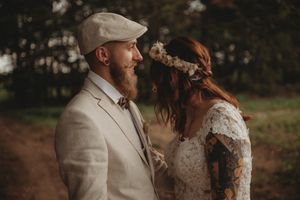 Intimate forest wedding portrait with beige suit and lace dress details.