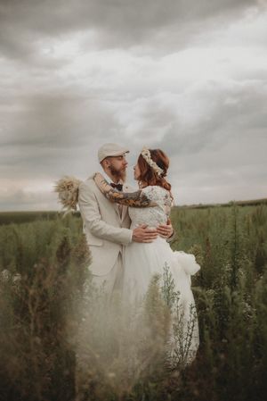 A moody wedding photo with the couple embracing against dramatic cloudy skies.