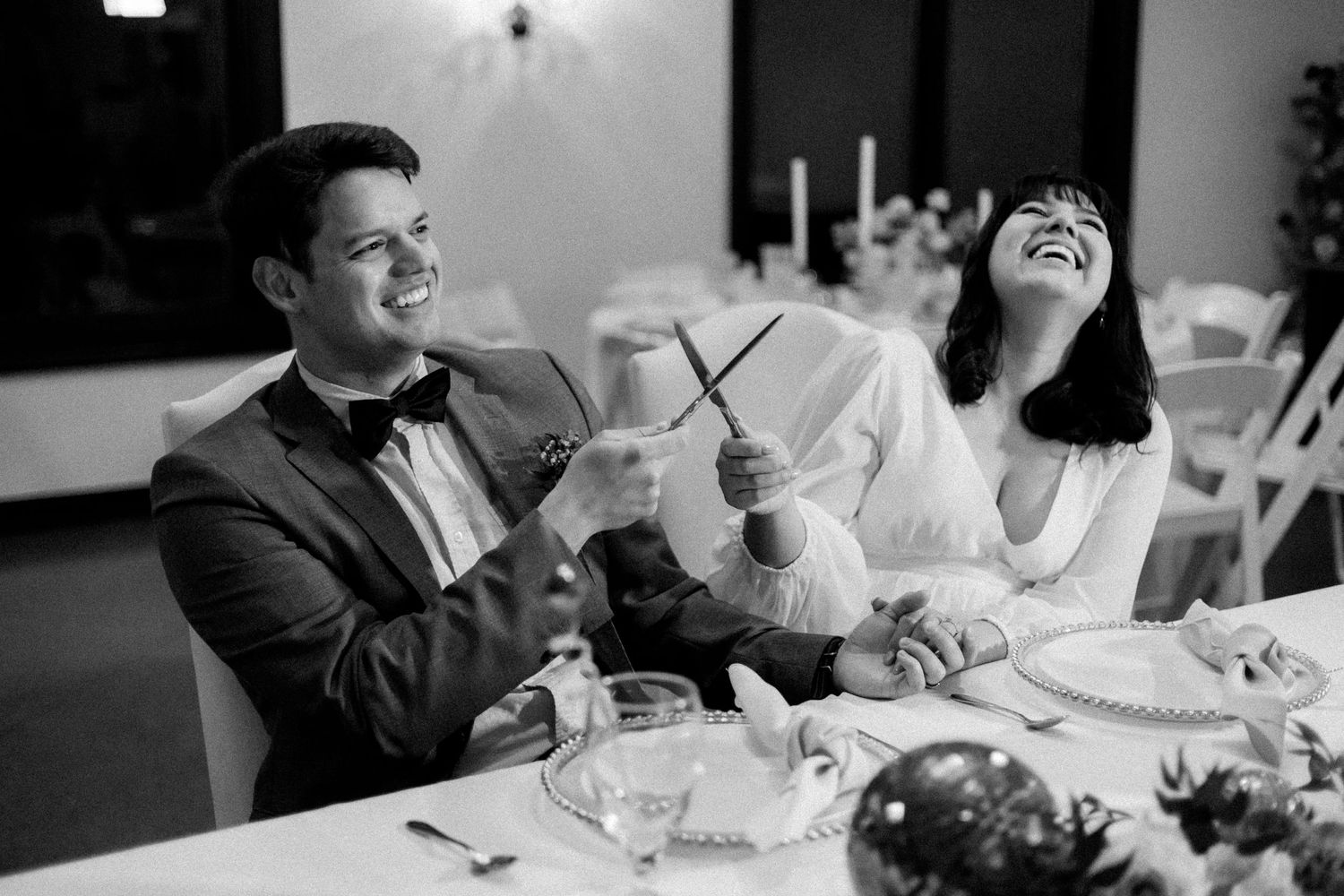 A couple shares a joyful moment while dining at their wedding reception.