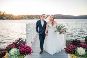 A couple poses on a lakeside dock decorated with pink flowers and ornamental cabbage at sunset at Candlewood Inn